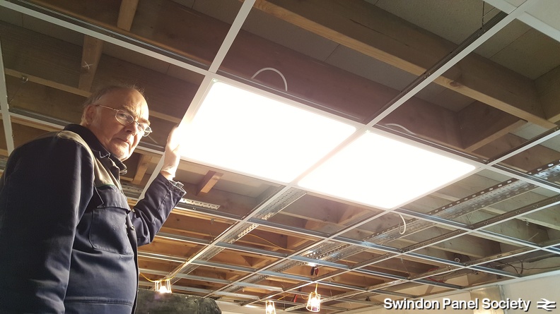 Let there be light! (1) - GWS electrician David Brown test fits the first LED fitment to the Panel Room suspended ceiling.