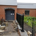 An updated building front entrance view, as fencing and railing posts continue to be worked upon.