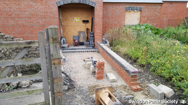 Outside, the new pathway boundary wall takes shape, with further works on the air-raid shelter (extreme left) also continuing apace.